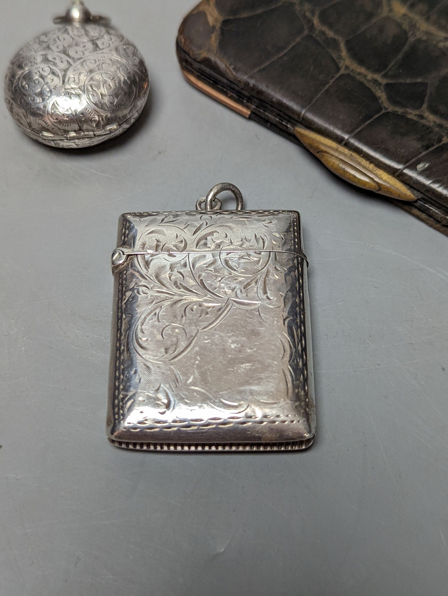 A late Victorian engraved silver sovereign case, a silver vesta case and an Edwardian 9ct gold mounted leather card purse.
